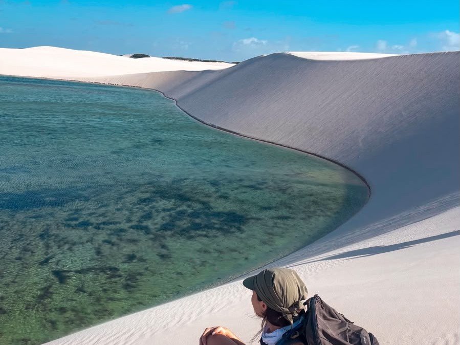 Lagoa de água cristalina encostada em uma grande duna nos Lençóis Maranhenses